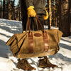 Person carrying a waxed canvas and leather log carrier. 