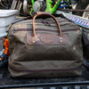 Frost River's waxed canvas and leather Prairie Boot Bag sitting in the back of a pickup truck with a dirt bike.  