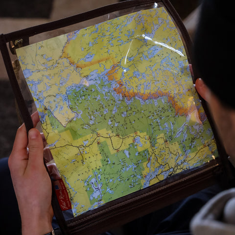 A person holding a map case with a map of the Superior National Forest