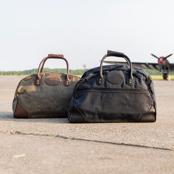 Waxed canvas and leather duffel bag sitting on an airstrip waiting for a plane. 