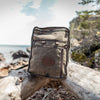 Waxed canvas Itasca pack sitting on a log on the edge of Lake Superior