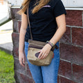 A woman wearing a waxed canvas shoulder bag crossbody. 